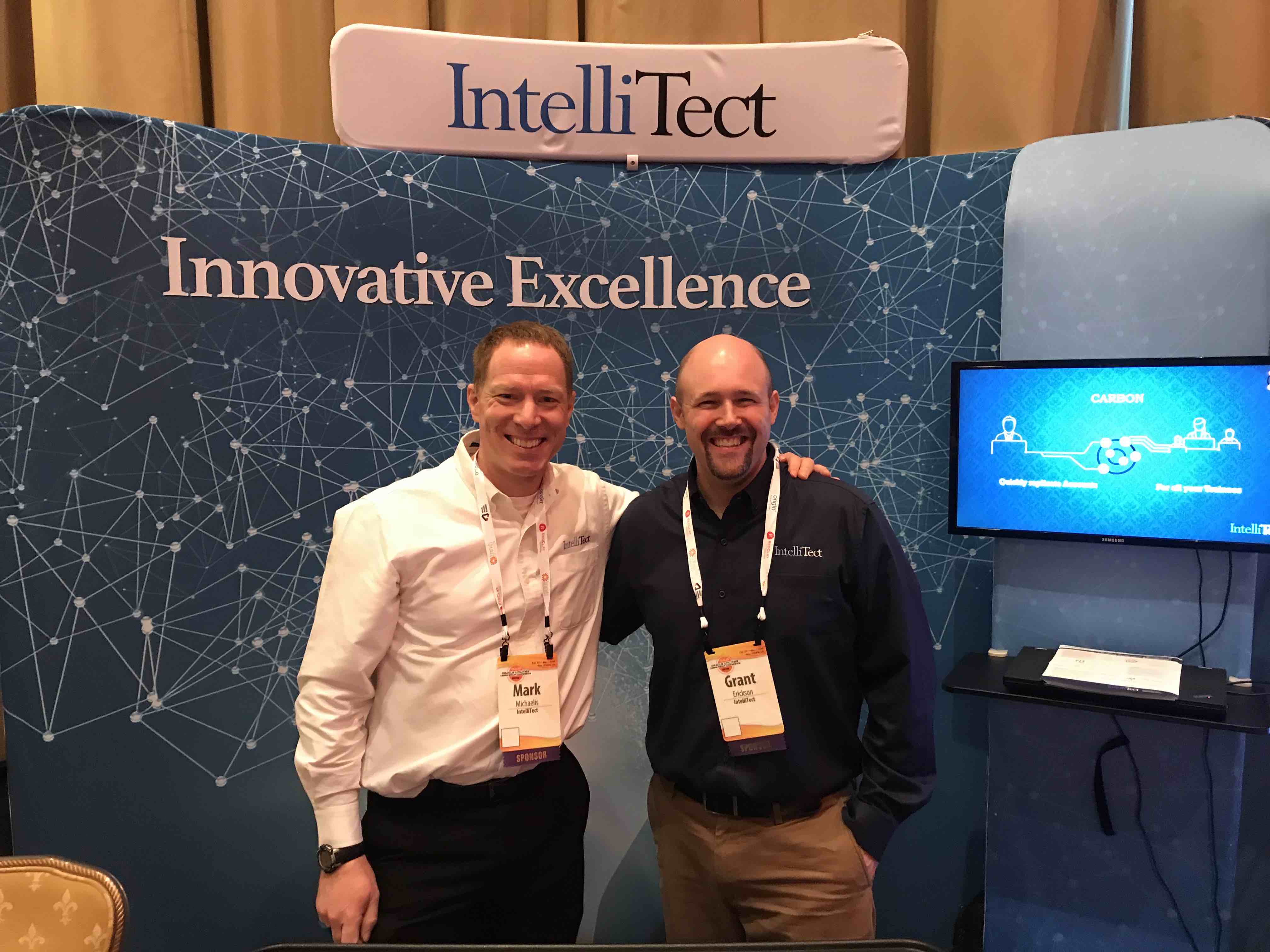 Mark Micahelis and Grant in front of an IntelliTect sign