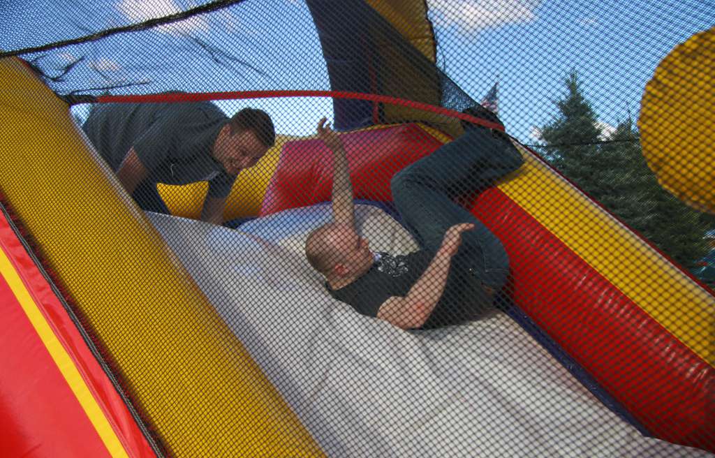 Two men falling down a slide as part of an obstacle course race at the IntelliTect company picnic